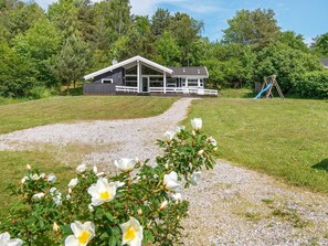 A modern house with a gravel driveway leading to a wooden deck. - 4 Star Holiday Home in Ebeltoft (Ebeltoft)