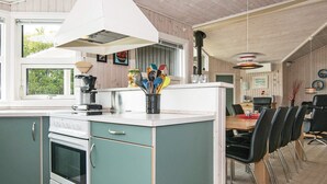 A kitchen with a stove, oven, and a dining area with chairs and a table. - 4 Star Holiday Home in Ebeltoft (Ebeltoft)