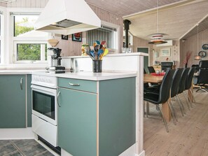 Ett kök med spis, ugn och en matplats med stolar och ett bord.