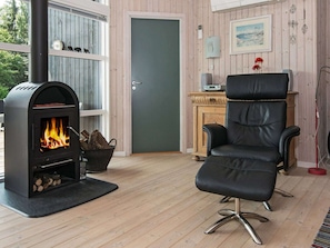 A room with a fireplace, a black leather chair, a door, and a window with a view of trees.