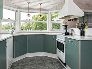 A kitchen with a built-in oven, a sink, and a window overlooking greenery. - 4 Star Holiday Home in Ebeltoft (Ebeltoft)