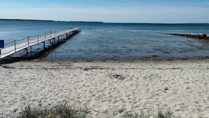 A beach with a wooden pier extending into the water, sandy shore, and clear sky. - 4 Star Holiday Home in Ebeltoft (Ebeltoft)