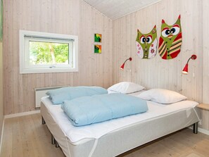 Ett sovrum med två sängar, ett fönster och dekorationer på väggarna.