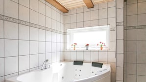 Une salle de bain avec une baignoire sur pieds, une fenêtre offrant une belle vue et un plafond en bois.