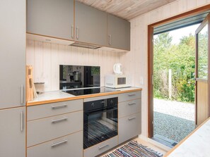 A modern kitchen with grey cabinets, a built-in oven, and a microwave on the countertop. - 4 Star Holiday Home in Bjert (Bjert)