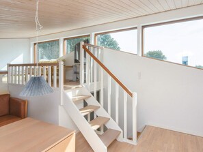 A modern interior with a staircase leading to an upper level, a hanging light fixture, and a view through large windows. - 4 Star Holiday Home in Bjert (Bjert)