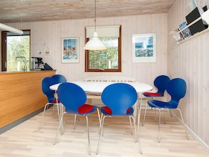 A dining area with a round table and blue chairs with red cushions, a hanging light fixture, and framed artwork on the walls. - 4 Star Holiday Home in Bjert (Bjert)