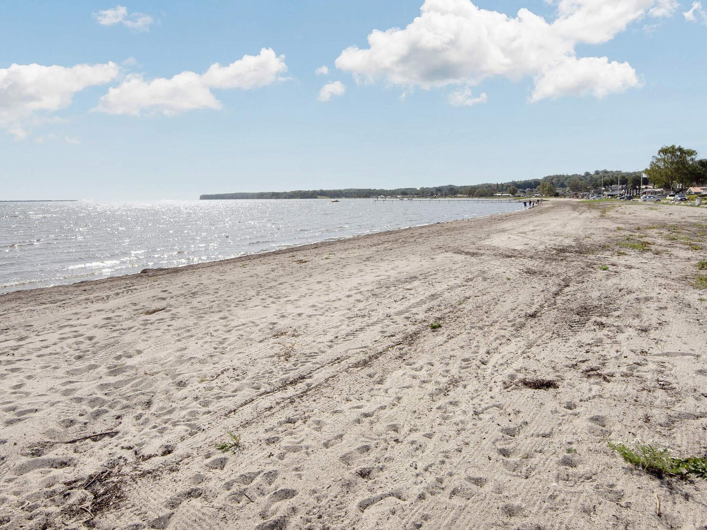 Ein sandiger Strand mit blauem Himmel und einer fernen Küstenlinie.