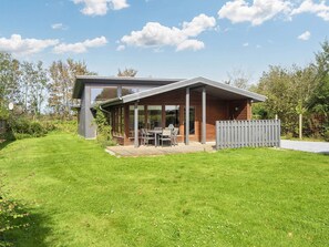 A modern house with a deck, a dining area, and a fenced yard. - 4 Star Holiday Home in Bjert (Bjert)