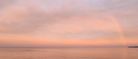 Una playa con un mar tranquilo y un arcoíris en el cielo.