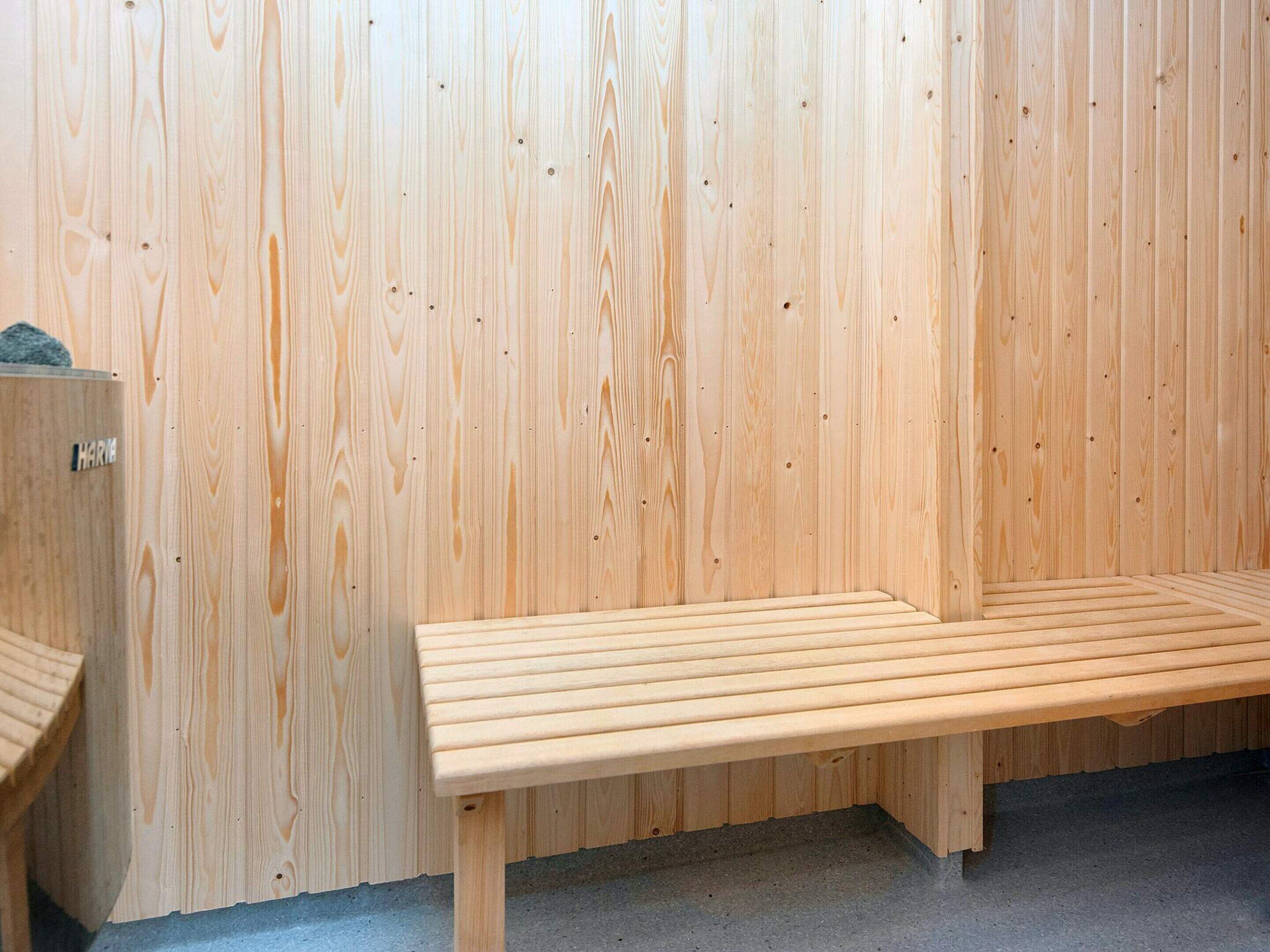 A wooden bench against a wooden wall, with a small wooden structure to the left.