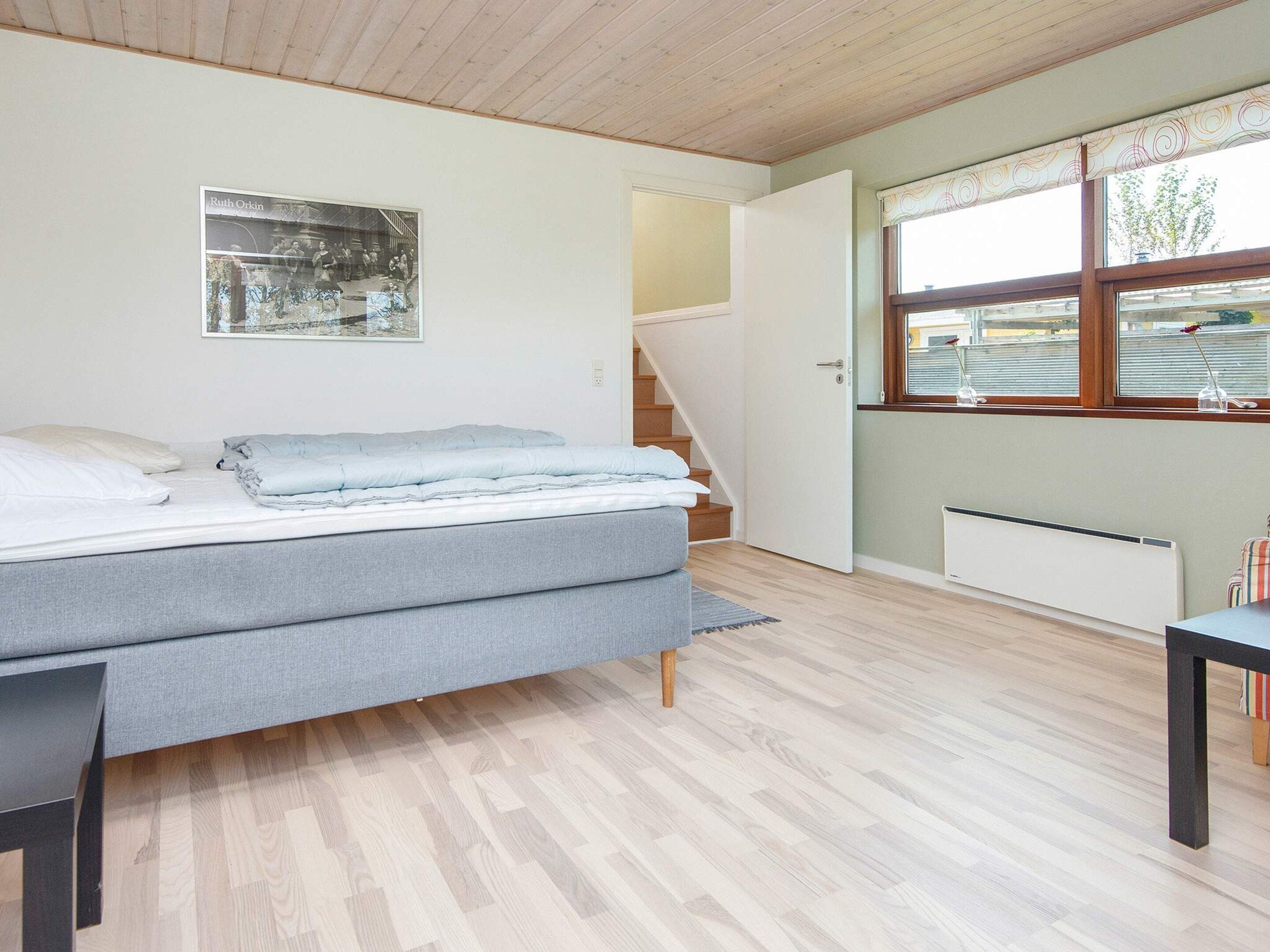 A bedroom with a bed, a window, a radiator, and a staircase.