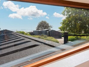 A view through a window with a clear sky, a tree, and a building with a sloped roof. - 4 Star Holiday Home in Bjert (Bjert)