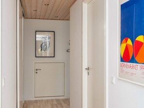 A hallway with a door, a framed artwork on the wall, and a poster on the adjacent wall. - 4 Star Holiday Home in Bjert (Bjert)
