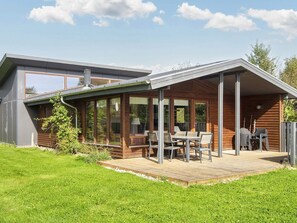 A modern house with a deck, large windows, and a dining area. - 4 Star Holiday Home in Bjert (Bjert)