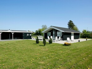 A modern house with a covered patio and a lawn.