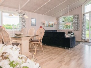 A spacious room with a dining area, a sofa, and a large window with curtains.