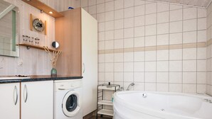 Une salle de bain moderne équipée d’un lave-linge, d’un évier et d’une baignoire.