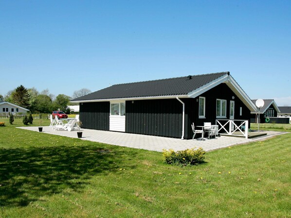A two-story building with a covered patio area, a car parked outside, and a lawn.