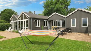 A two-story house with a patio area, a hammock, and a barbecue grill. - 4 Star Holiday Home in Nysted (Nysted)