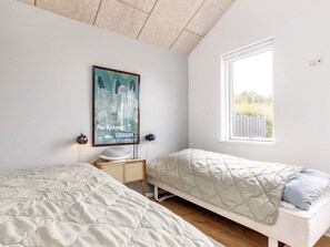 A bedroom with two beds, a window with a view, a wall-mounted artwork, and a small table with a lamp. - 4 Star Holiday Home in Nysted (Nysted)