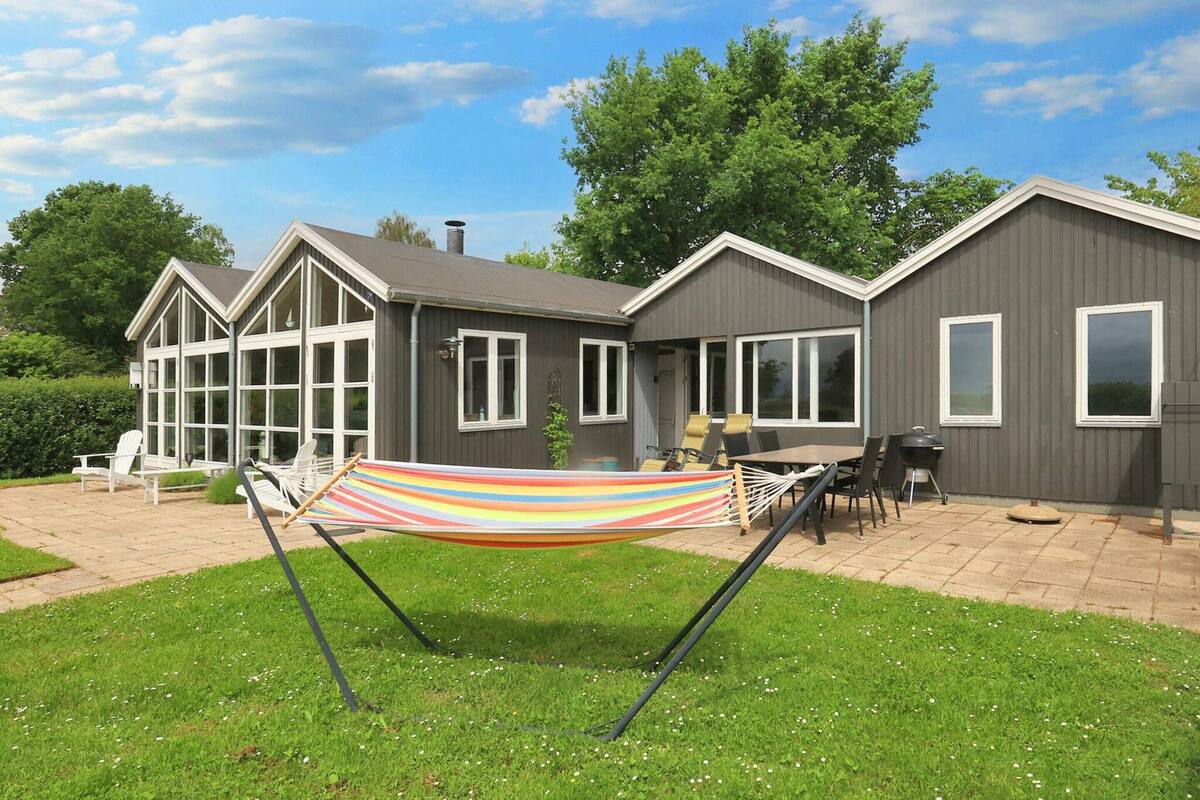 A two-story house with a patio area, a hammock, and a barbecue grill.