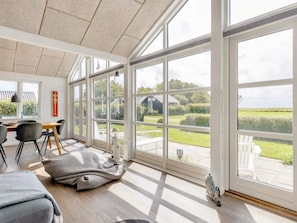 A spacious room with large windows, a dining area, and a view of the outdoors. - 4 Star Holiday Home in Nysted (Nysted)