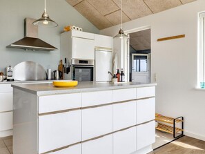 A modern kitchen with a large island, stainless steel appliances, and a hanging light fixture. - 4 Star Holiday Home in Nysted (Nysted)