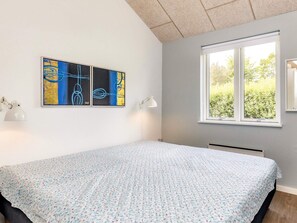 A bedroom with a bed, a window, and abstract art on the wall.