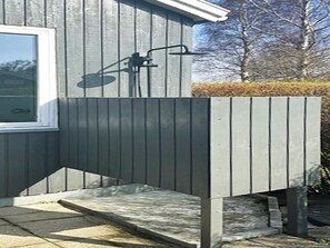 A modern outdoor shower with a step leading up to it, a window to the left, and a wooden fence in the background. - 4 Star Holiday Home in Nysted (Nysted)