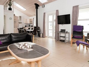 Un salon moderne comprenant un canapé, une table basse, un téléviseur et un coin repas avec des chaises.