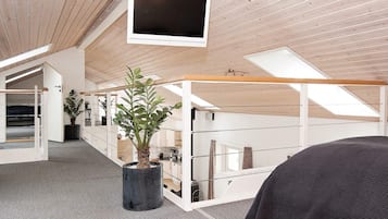 A modern interior with a ceiling-mounted TV, a potted plant, and a bed.