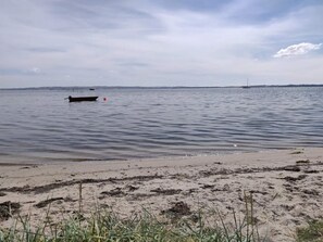 A beach with calm water, a boat, and distant land. - 5 Star Holiday Home in Ega (Aarhus)