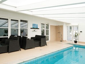 An indoor swimming pool area with a seating arrangement and a shower.