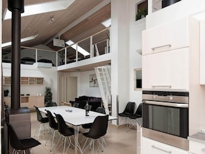 A modern kitchen with a high ceiling, a dining area with a table and chairs, and a loft space with a staircase. - 5 Star Holiday Home in Ega (Aarhus)