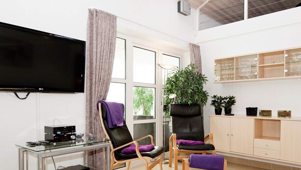 Una sala de estar moderna con una televisión de pantalla plana, dos sillones de cuero, una mesa de centro de vidrio, una planta en maceta y un mueble de madera.