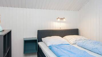 A bedroom with a bed, a nightstand, and a wall-mounted light fixture.