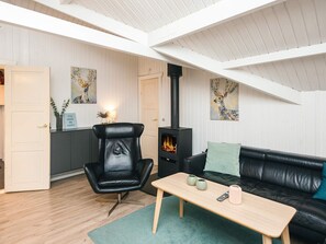 A cozy living room with a black leather chair, a black sofa, a wooden coffee table, and a black wood-burning stove. - 6 Person Holiday Home in Toftlund (Toftlund)