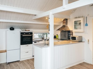 A modern kitchen with white cabinetry, a built-in oven, a microwave, and a large window providing natural light. - 6 Person Holiday Home in Toftlund (Toftlund)