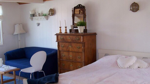 Um quarto com cama, cômoda, cadeira e sofá azul.
