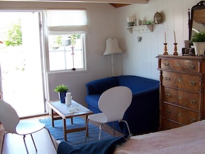 A room with a blue armchair, a white chair, a wooden dresser, and a small table with a plant and candles. - 4 Person Holiday Home in Ronnang (Roennaeng)