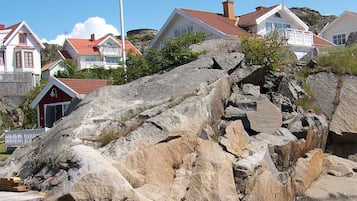 A rocky terrain with a wooden dock, surrounded by houses with red roofs and white walls.