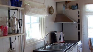 Uma cozinha compacta com pia, chaleira e fogão.