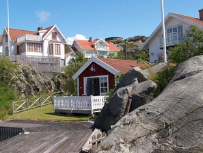 A coastal residential area with houses, a red building, and large rocks. - 4 Person Holiday Home in Ronnang (Roennaeng)