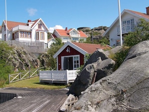 A coastal residential area with houses, a red cabin, and a rocky landscape. - 4 Person Holiday Home in Ronnang (Roennaeng)