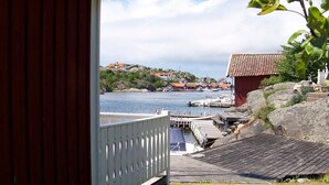 A coastal view with a wooden dock, a red building, and a clear sky. - 4 Person Holiday Home in Ronnang (Roennaeng)