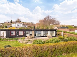 A modern house with a flat roof, large windows, and a garden.