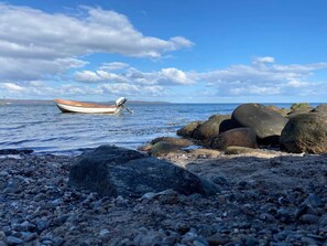 Una costa rocosa con un bote varado entre las rocas.