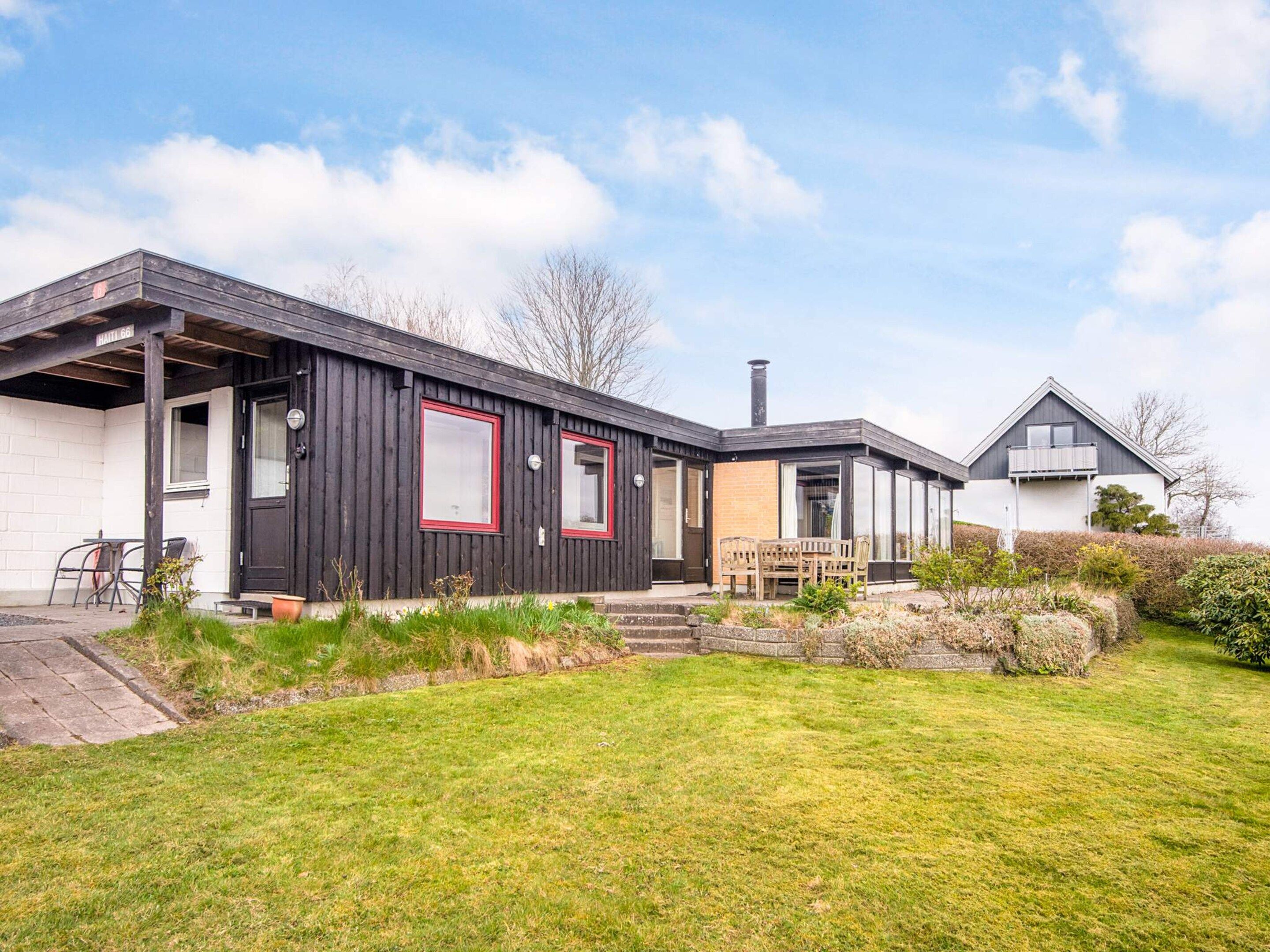 A modern two-story house with a flat roof, a chimney, and a well-maintained lawn.