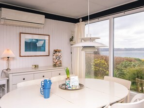 A dining area with a white table, blue cups, a decorative plant, and a view of the water. - 6 Person Holiday Home in Borkop (Borkop)